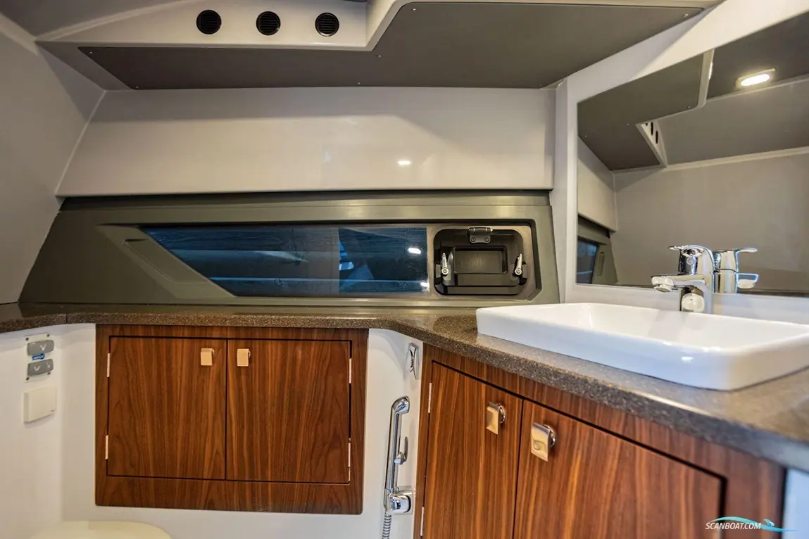 Modern boat bathroom featuring wooden cabinetry, a countertop sink, mirrors, and a large window providing natural light.